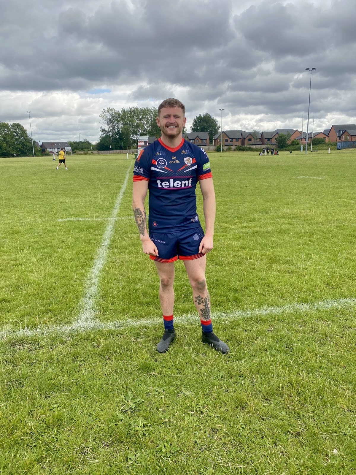 man wearing blue and red sports clothing at a rugby field.