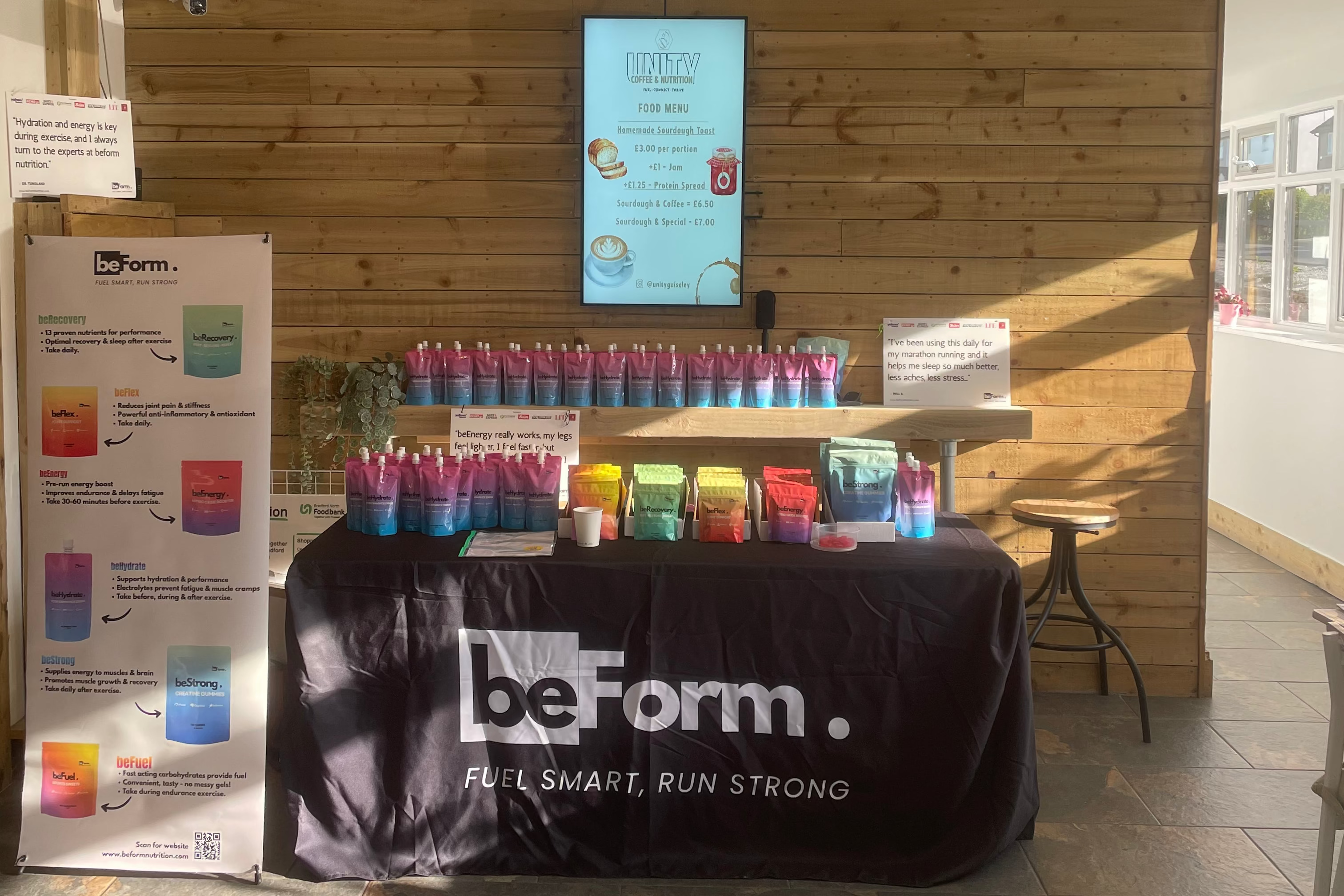 BeForm booth with colorful bottles and digital display at an event.