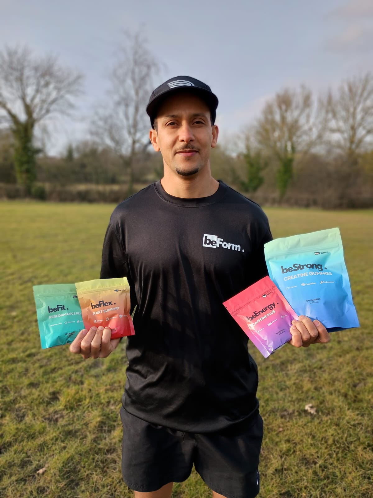 Man holding various 'beForm' supplement packets in an outdoor setting