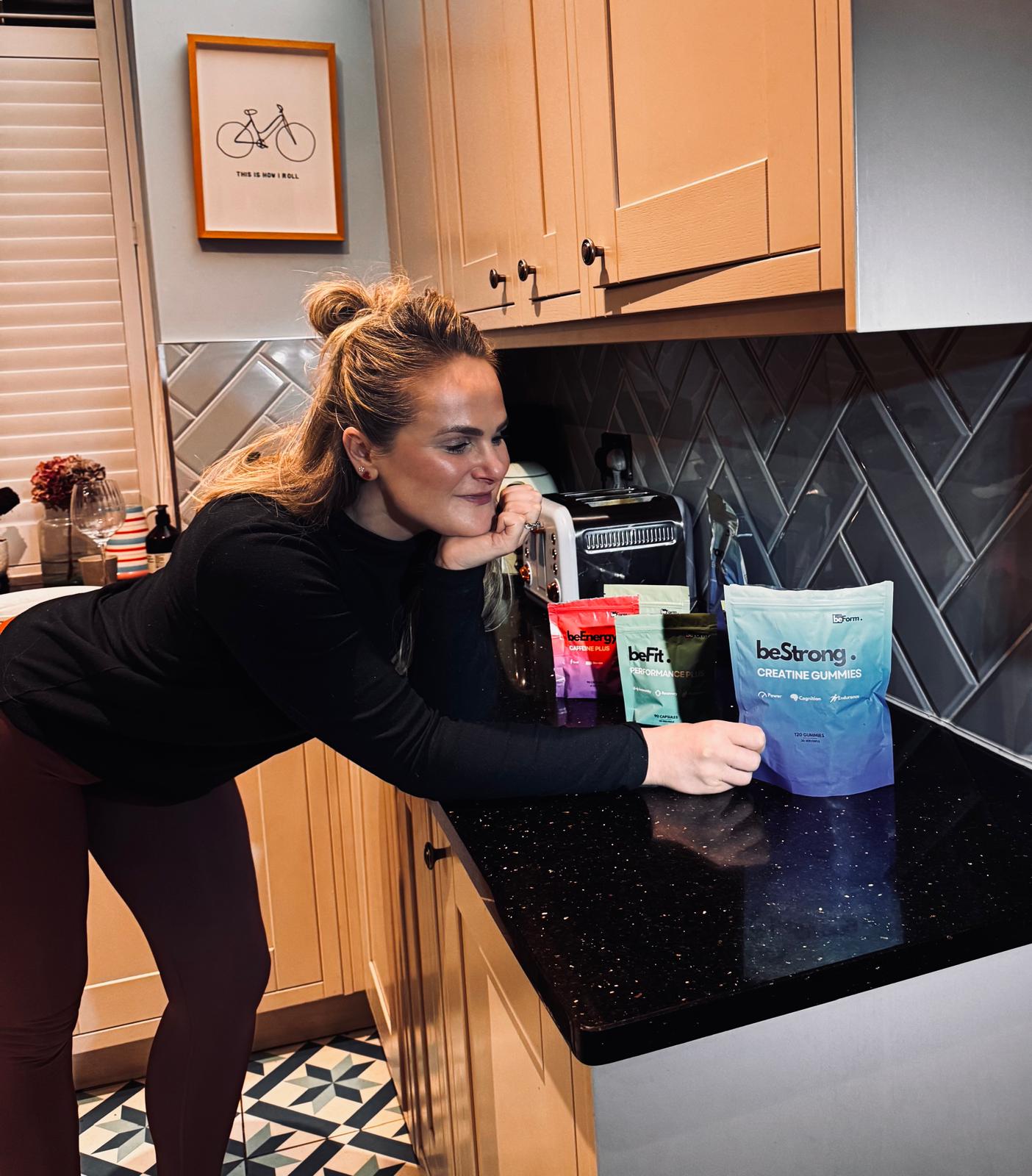 Woman in a kitchen with beStrong supplement bags on the counter