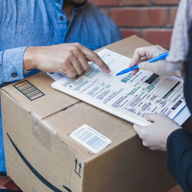 Two people inspecting a package with a checklist on a box.