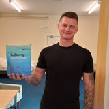 Person holding a blue packet of bestrong in an indoor setting