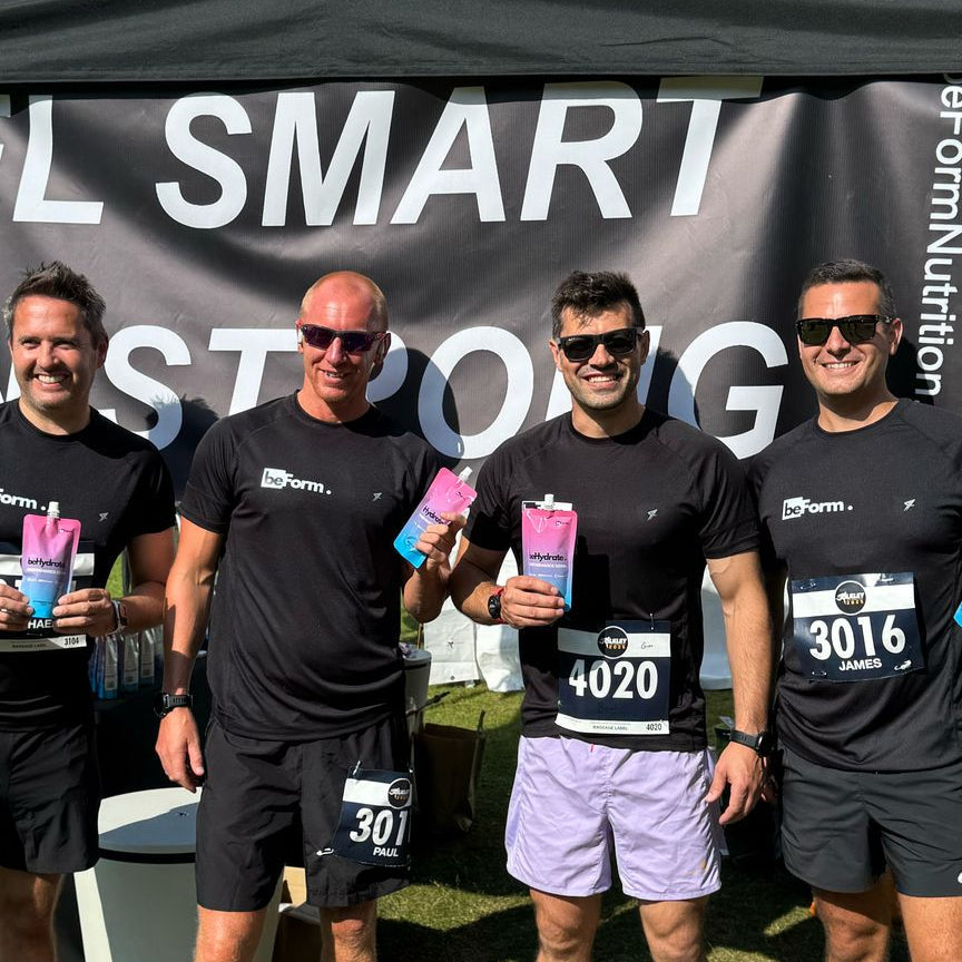 Four men in running gear standing in front of a beForm Nutrition 'Fuel Smart Run Strong' tent with a banner.