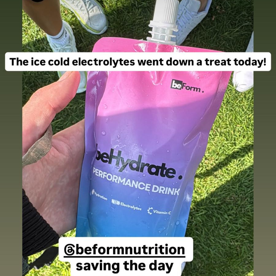 Fire Fighter holding a BeHydrate performance drink pack with grass in the background