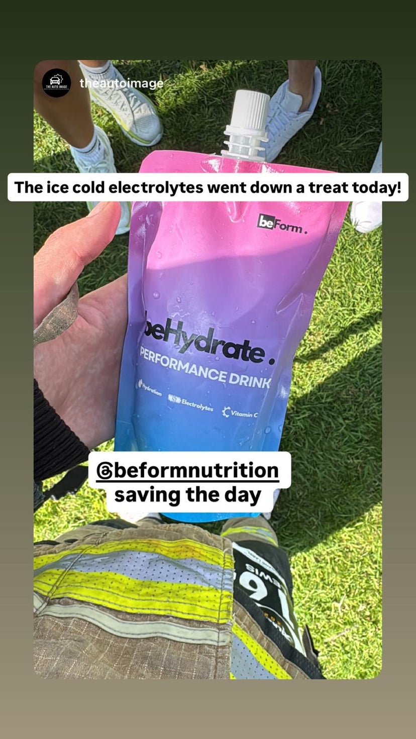 Fire Fighter holding a BeHydrate performance drink pack with grass in the background