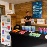 Man standing behind a table with packets of sports nutrition packets from beForm nutrition in a wooden interior of a gym setting