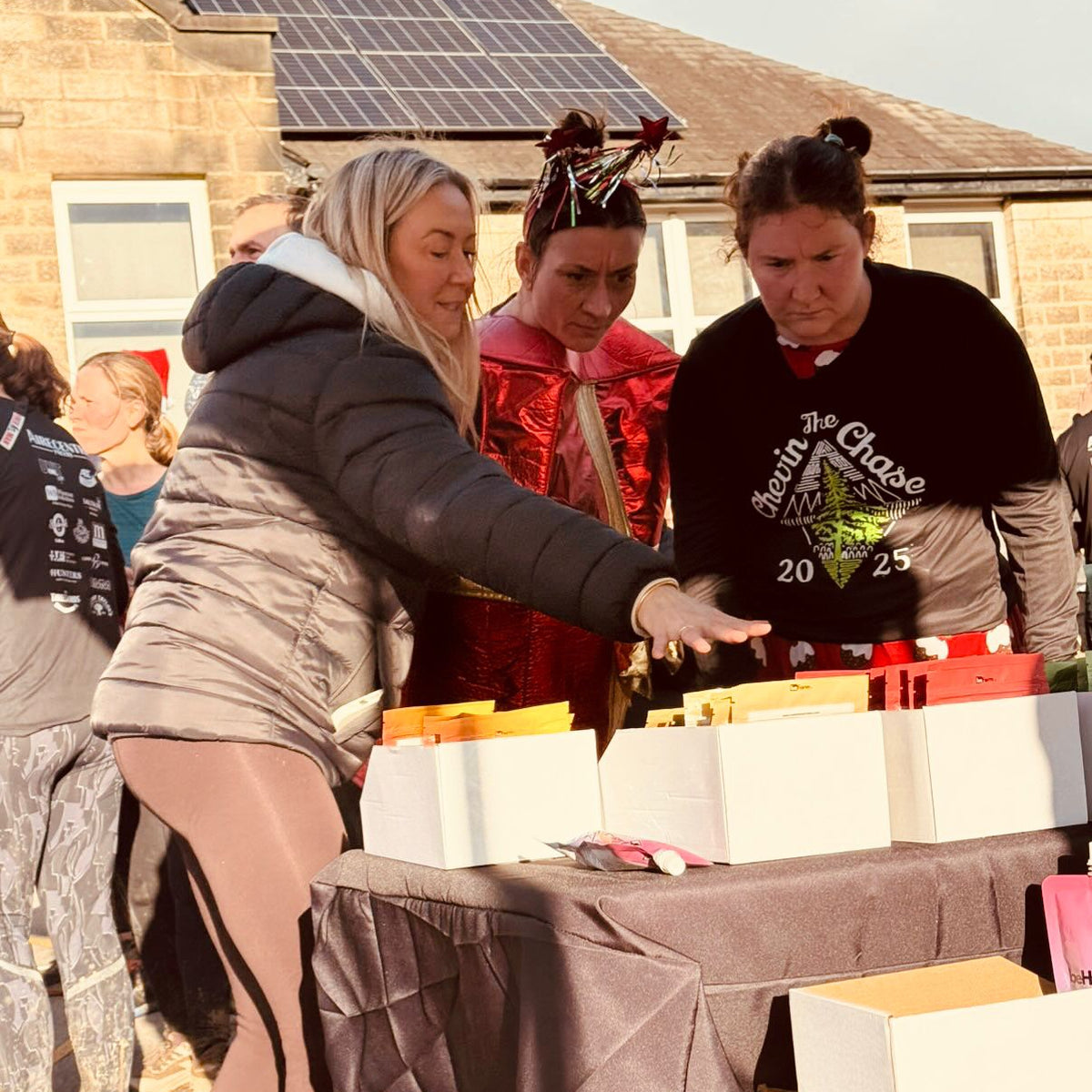 People gathered around a table with boxes outdoors, at a running event or gathering.