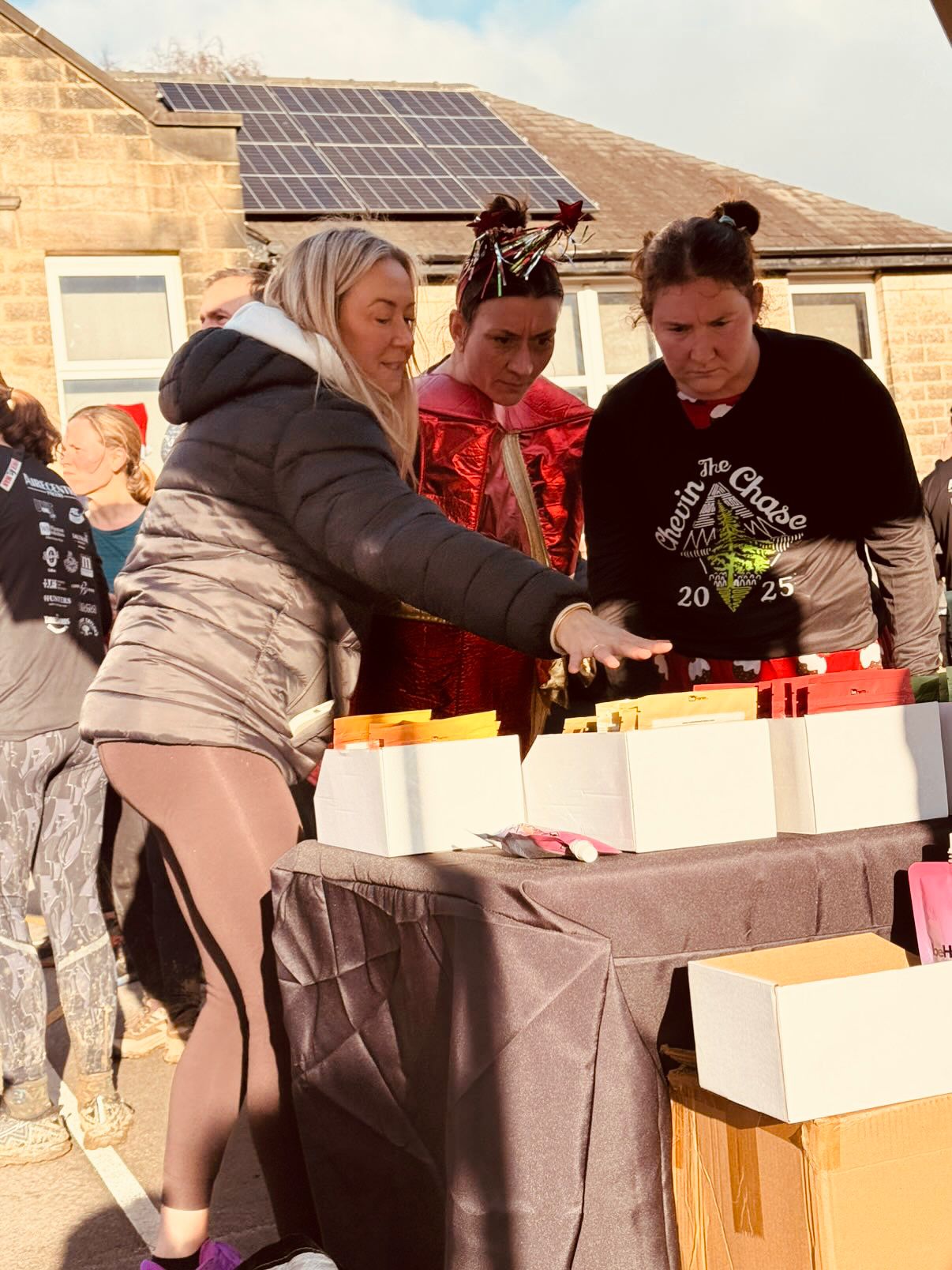People gathered around a table with boxes outdoors, at a running event or gathering.