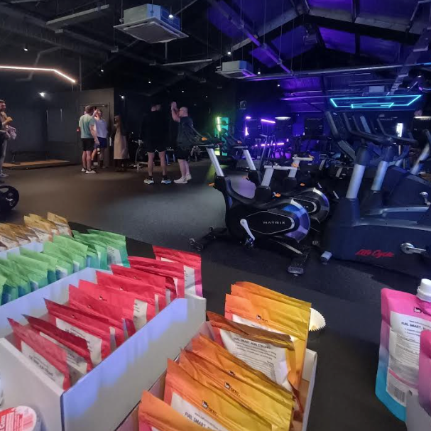 Gym interior with exercise equipment and colorful beform nutrition packets on a counter.