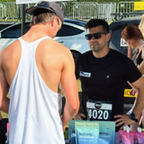 two people at a running event talking in front of a table with bestrong packages on the table.