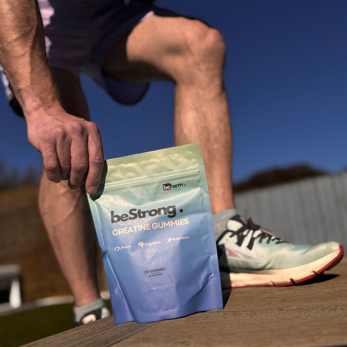 Person holding a blue package of creatine gummies outdoors.