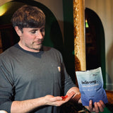 Man holding a blue 'beStrong' packet and red candies in a casual setting.