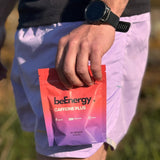 Person holding a red energy supplement packet in a natural setting