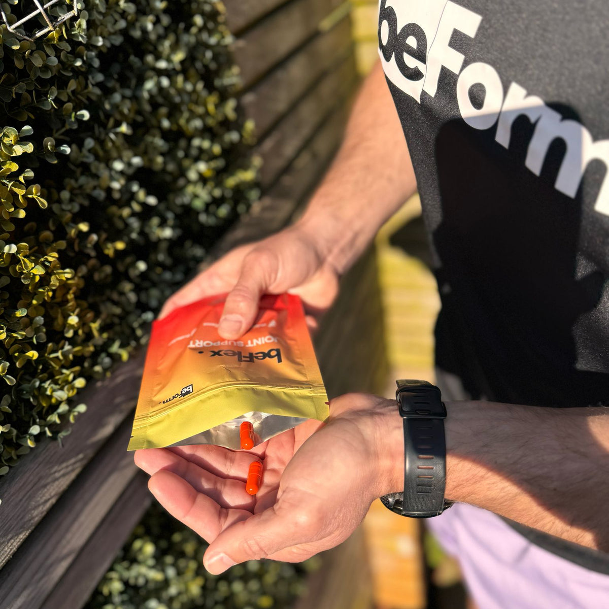 Person opening a packet of beFlex with an orange capsule standing outdoors.