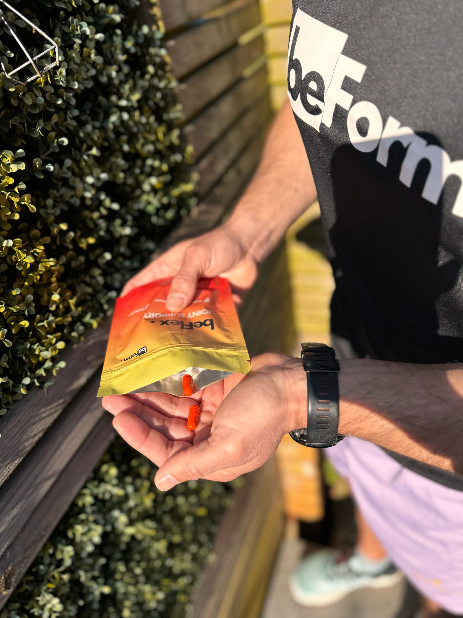 Person opening a packet of beFlex with an orange capsule standing outdoors.