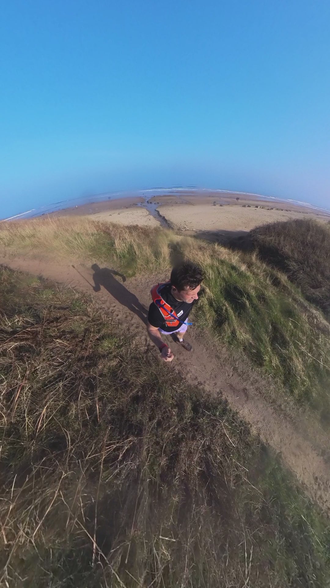 man running through sand dunes